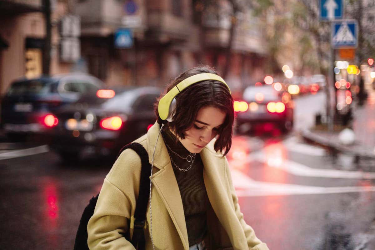 Young woman listening to music in headphones while walking in a city